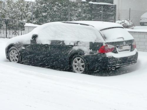 Der BMW verschwindet unter einer dichten Schneekappe. 
