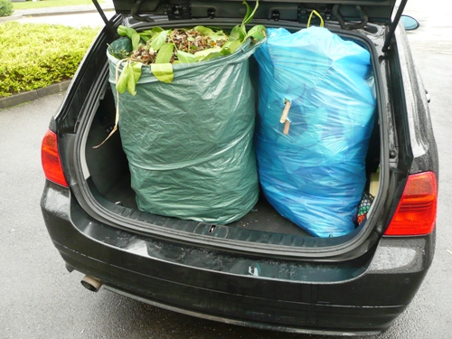 Der Kofferraum des BMW ist mit den in blauen Müllsäcken verpackten Resten der Aufräumarbeiten im Garten gut gefüllt. Der Kofferraum des BMW ist mit den in blauen Müllsäcken verpackten Resten der Aufräumarbeiten im Garten gut gefüllt.