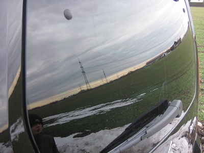 Ein winterliches Feld spiegelt sich in der Scheibe. Spiegelung in der Heckscheibe.