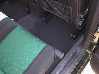 Das Foto zeigt einen Teil der Rücksitzbank auf der Beifahrerseite mit festgezurrter Laderaumabdeckung. Sehr deutlich ist zu erkennen, dass die Laderaumabdeckung einige Zentimeter übersteht und dadurch den Einstieg behindern kann. 