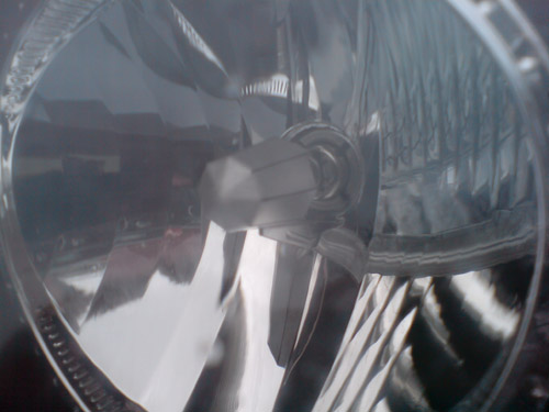 Blick durch das Klarglas des Scheinwerfers vorne links auf das H7-Leuchtmittel von Unitec. Reflektor des Abblendlichts im Klarglasscheinwerfer vorne links.