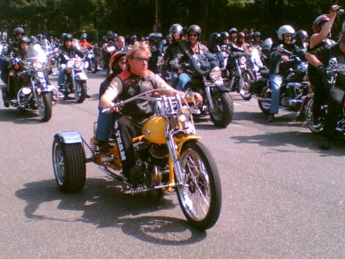 Vater und Sohn auf orangem Harley-Custom-Threewheeler. 